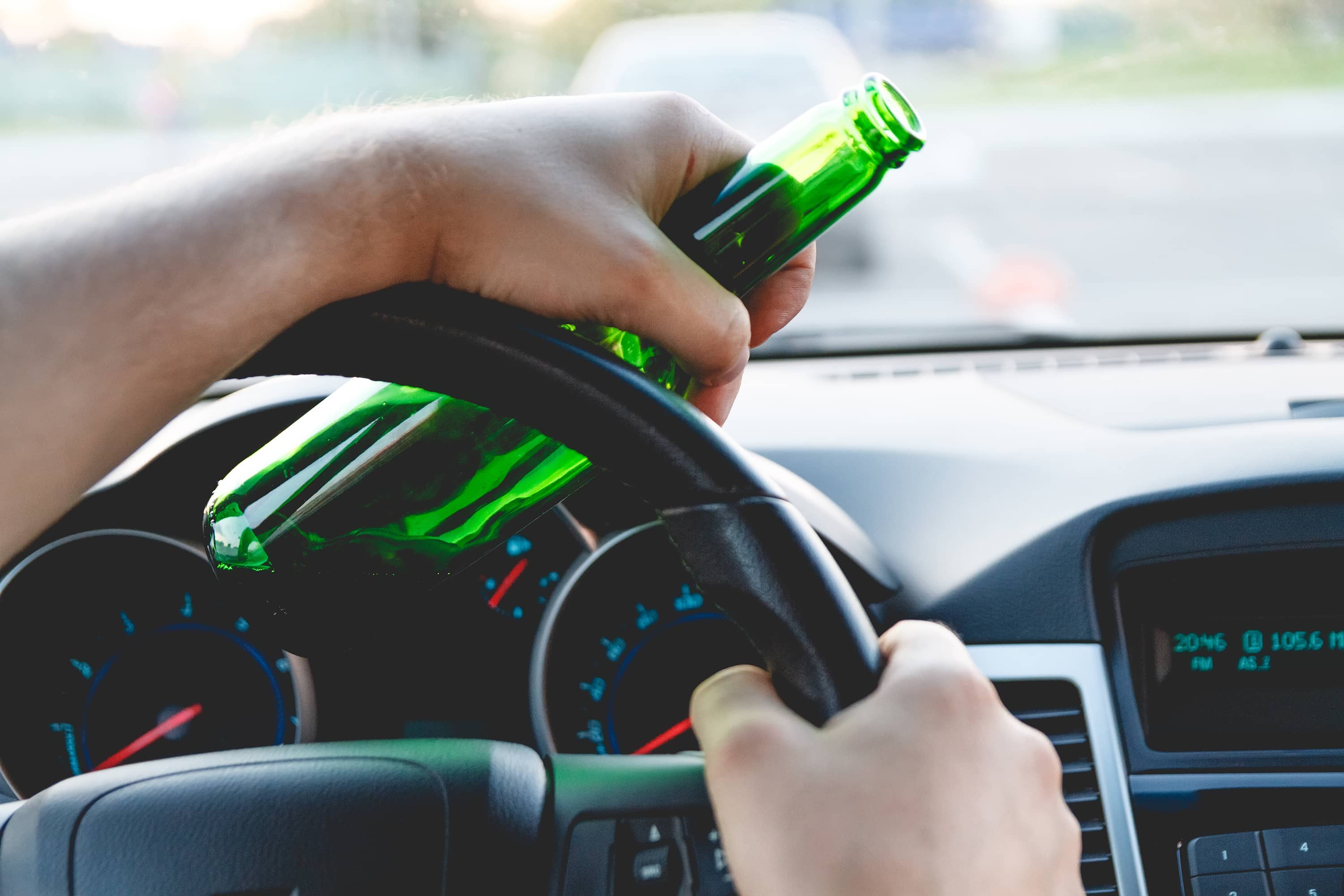 Man behind a steering wheel, holding a drink after leaving a stadium