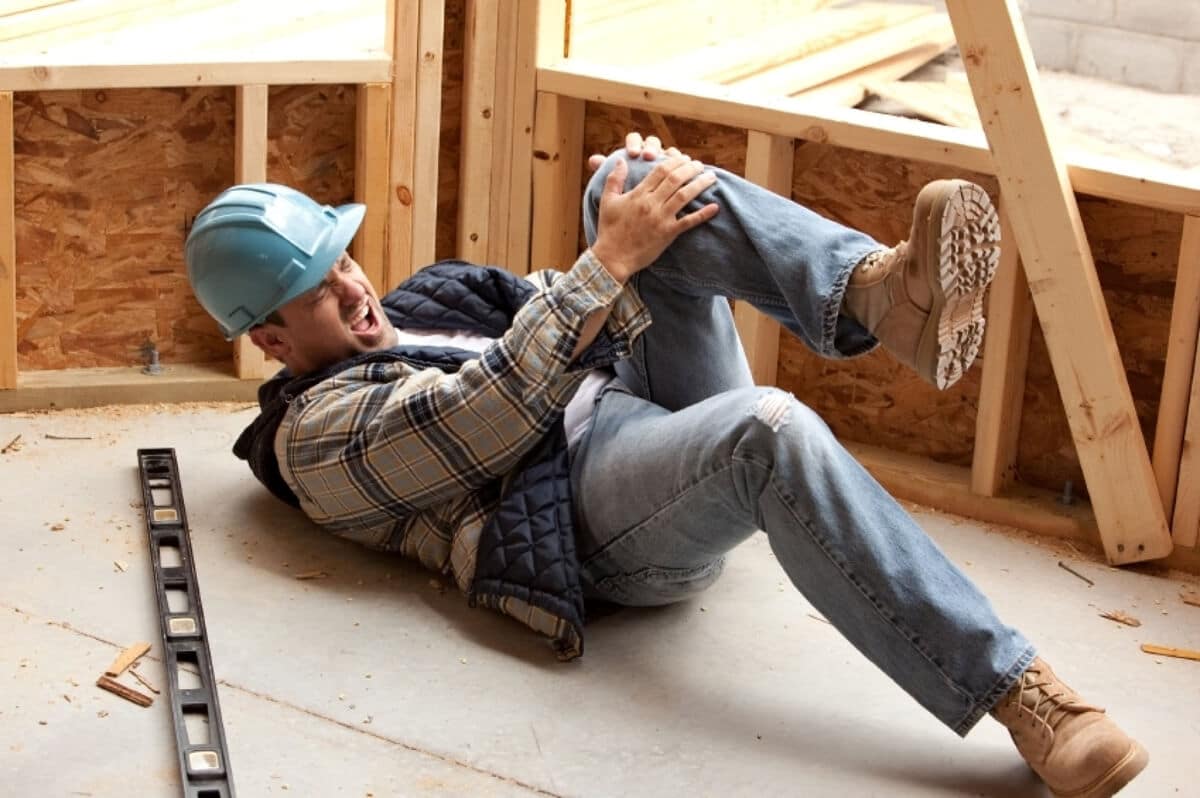 Construction Worker Holding His Knee on the Ground After Injury