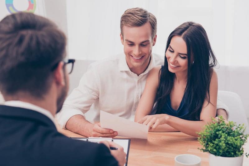 A Couple In A Layers Office Reading Papers And Smiling